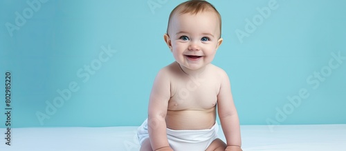 A delightful infant wearing a diaper photographed against a soft light blue background providing ample space for text photo