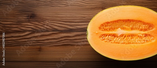 A cut cantaloupe melon photographed from above on a wooden cutting board with ample copy space in the image photo