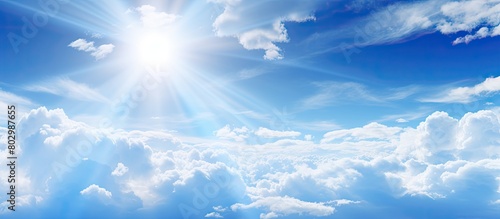 A copy space image of sunlight filtering through white clouds against a blue sky backdrop