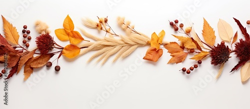 A creative composition for autumn with a wreath crafted from dried flowers and dry leaves sitting on a white background This fall concept showcases an autumn background with a flat lay and top view l