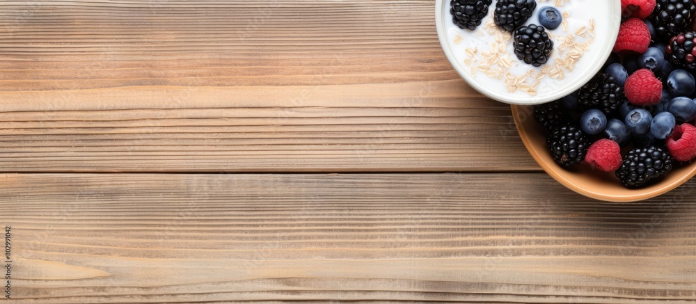 A breakfast bowl of yogurt oatmeal blueberries blackberries and chia seeds is beautifully displayed on a rustic wooden surface in a top down view leaving ample room for text or a caption in the copy