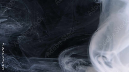 Wisps of smoke intertwine gracefully against a dark backdrop. (ID: 802995416)