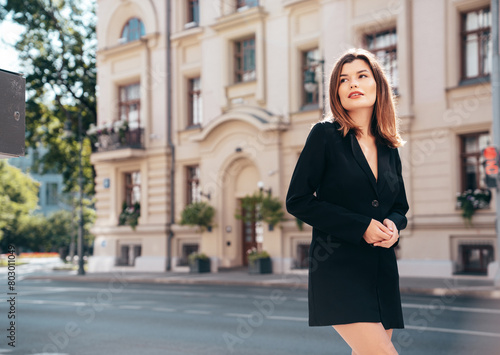 Portrait of young beautiful brunette woman wearing nice trendy suit black jacket clothes. Sexy smiling model posing in the street at sunny day. Fashionable female outdoors. Cheerful and happy © halayalex