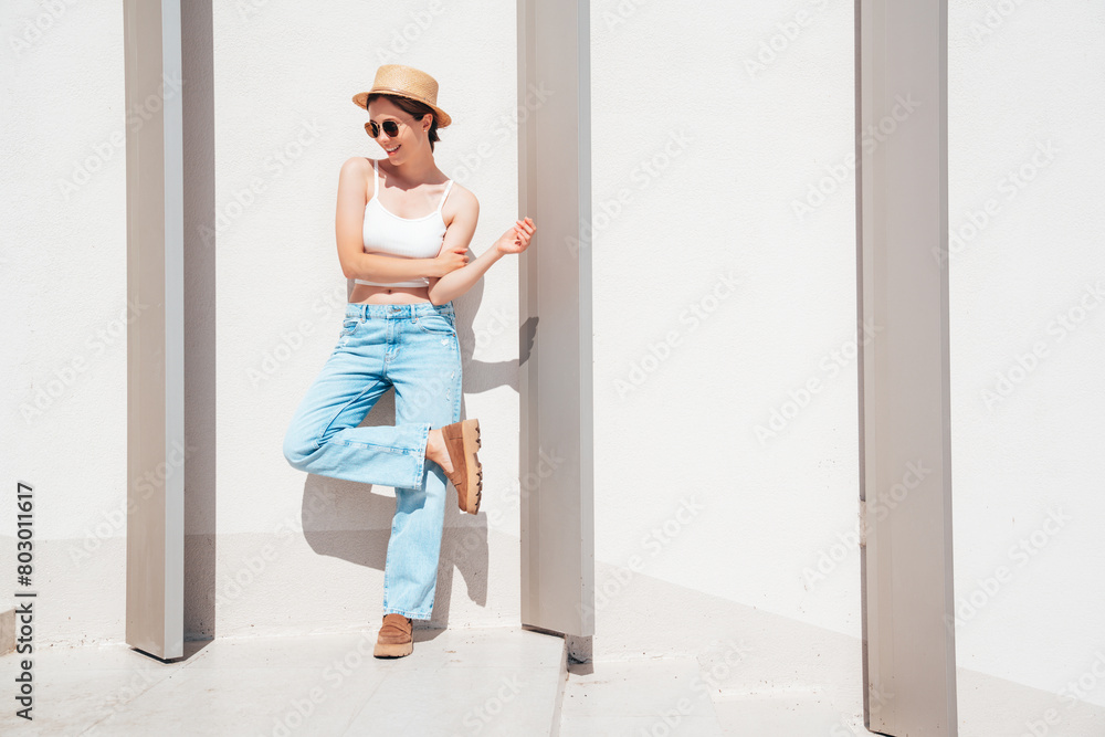 Beautiful smiling model in sunglasses. Female dressed in summer hipster white T-shirt and jeans. Posing near white wall in the street. Funny and positive woman having fun outdoors, in hat, sunglasses Beautiful smiling model in sunglasses. Female dressed in summer hipster white T-shirt and jeans. Posing near white wall in the street. Funny and positive woman having fun outdoors, in hat, sunglasses