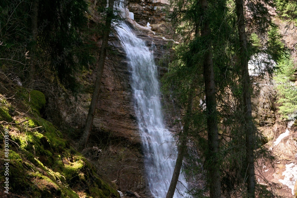 A high waterfall flows down among the rocks and trees in the forest A high waterfall flows down among the rocks and trees in the forest