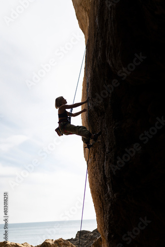 A woman is climbing a rock wall with a rope