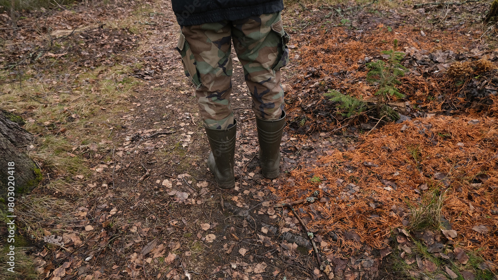 Feet in rubber boots on a forest, rural road. Feet in rubber boots on a forest, rural road.