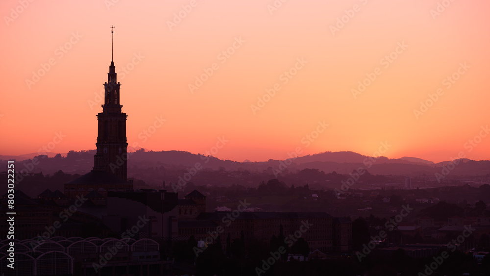 Naklejka premium Backlit sunset of a landscape with a tall tower. Gijon - Asturias