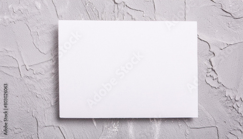 Mock-up of white blank card sheet of paper on gray cement textured surface. Postcard template.