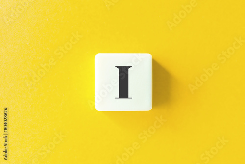 Capital Letter I. Text on Block Letter Tiles against Yellow Background.