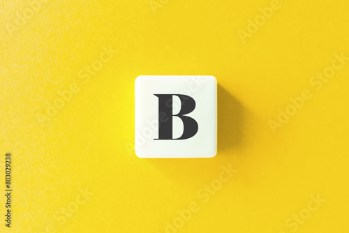 Capital Letter B. Text on Block Letter Tiles against Yellow Background.