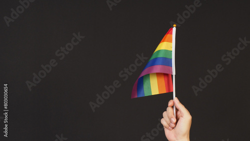 Hand is hold Rainbow pride flag on black ackground. photo