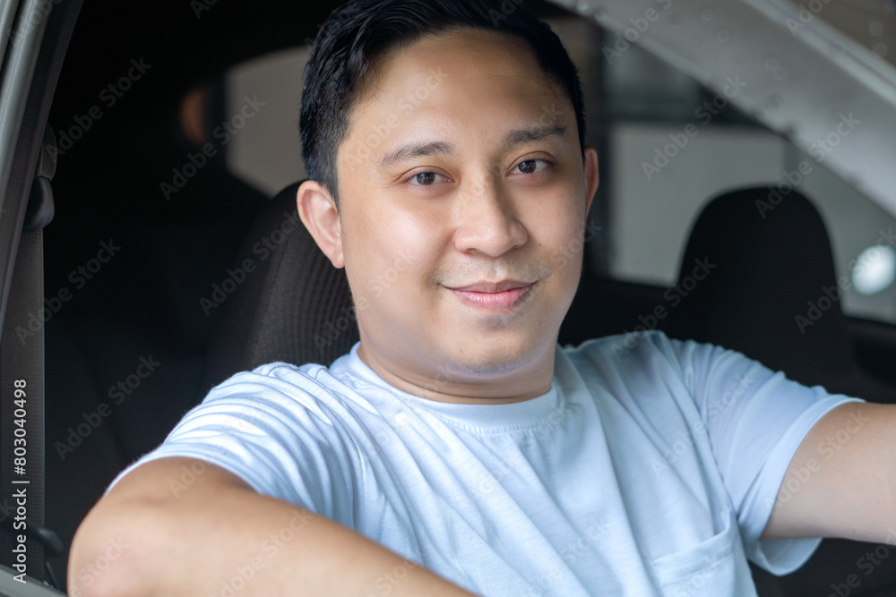 Asian man smiling to camera while driving his car Asian man smiling to camera while driving his car