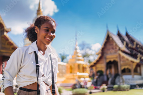 happy black tourist girl taking picture using vintage camera at temple. teenage african american using vintage camera taking temple photo. solo traveler relax doing photo shoot of thailand landmark photo