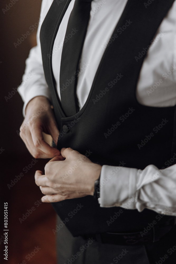 A man in a black suit and white shirt is adjusting his tie. Concept of formality and attention to detail, as the man carefully straightens his tie A man in a black suit and white shirt is adjusting his tie. Concept of formality and attention to detail, as the man carefully straightens his tie