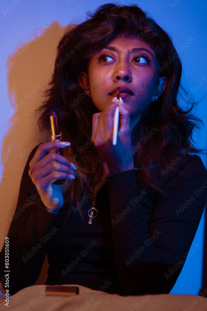 Fototapeta premium A woman is applying lipstick while holding a lipstick tube