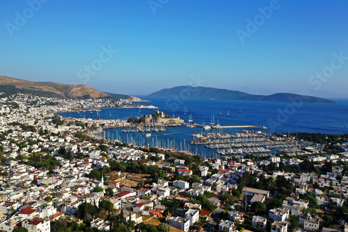Bodrum city aerial shot. Aegean sea, traditional white houses, flowers, marina, sailing boats, yachts in Bodrum town Turkey. 