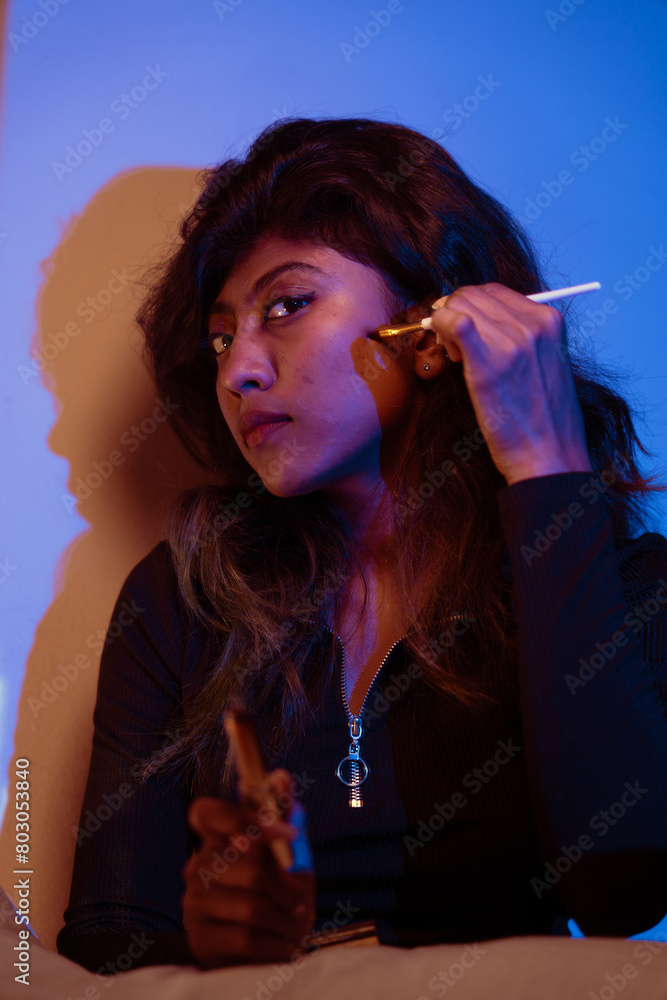Fototapeta premium A woman is sitting on a bed and holding a cell phone