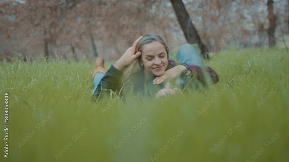 Couple holding each other while lying on grass in a forest Couple holding each other while lying on grass in a forest