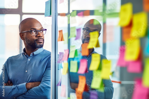 An entrepreneur at a brainstorming session with  radical innovation  sticky notes on a glass wall.