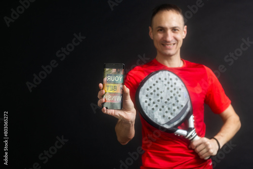 man holding paddel racket and smartphone with bet black background