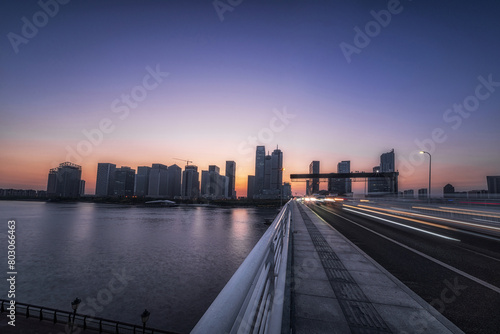 Riverside Dusk with Cityscape and Light Trails on Bridge © evening_tao