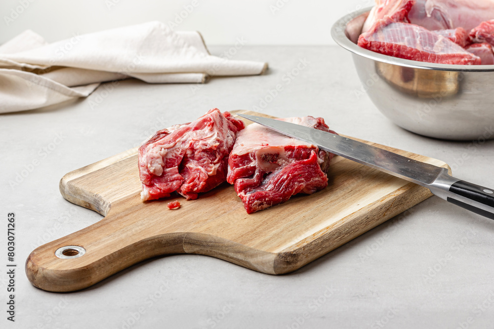 Raw beef ribs on wooden cutting board with knife