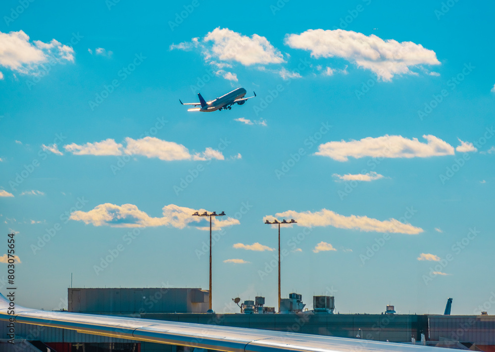 Fototapeta premium Airplane taking off in blue sky with some clouds.