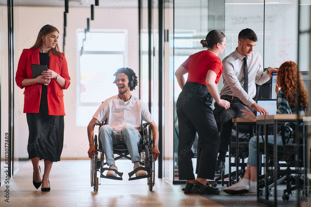 Fototapeta premium A business leader with her colleague, an African-American businessman who is a disabled person, pass by their colleagues who work in modern offices