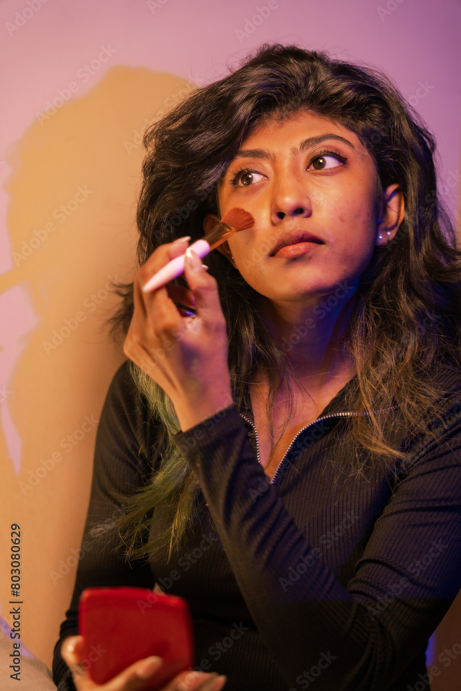 A woman is applying makeup in front of a wall A woman is applying makeup in front of a wall