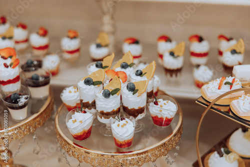 A table full of desserts with a variety of flavors and colors. The desserts are arranged in small cups and bowls, and there are also some cakes and pastries