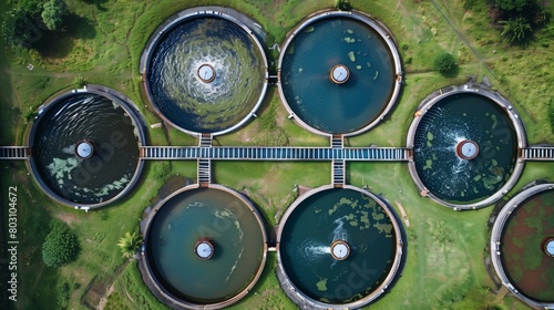 Aerial view of a water treatment facility with multiple circular tanks in a green landscape.