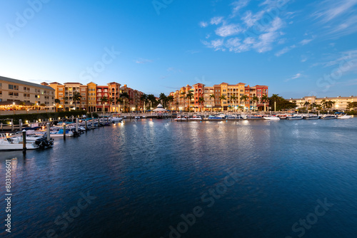 Twilight settles on Naples with waterfront buildings and boats under a clear sky.