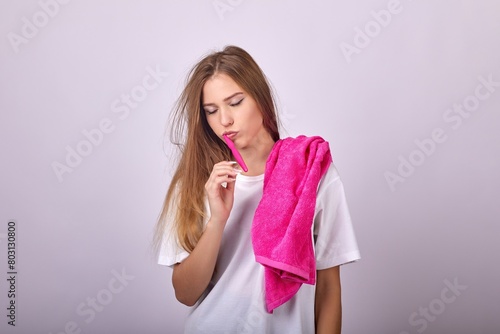 A young woman in a large white T-shirt is brushing her teeth with a toothbrush with her eyes closed. A woman cannot wake up holding a toothbrush to her mouth.