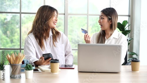 Two Asian female roommates holding credit cards, shopping online, holding credit card in bedroom at apartment photo