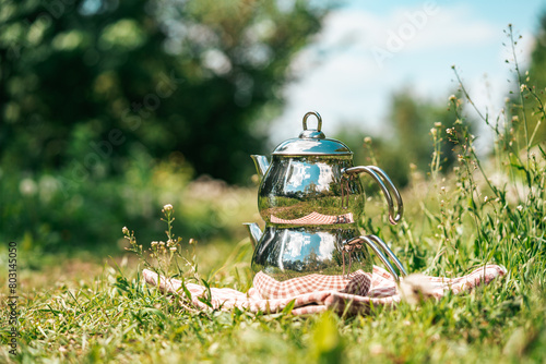 Traditional Turkish double tea pot kettle on a green medow. Making Turksih tea outdoors with beautiful summer atmosphere all around.
