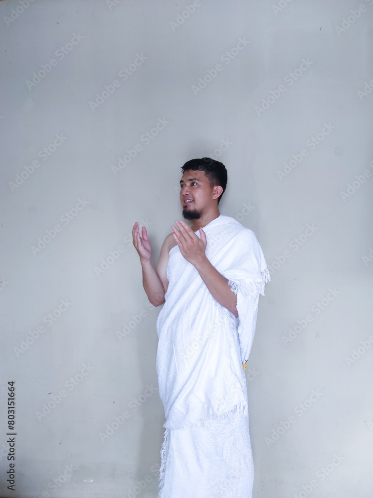 Muslim man praying while standing wearing ihram cloth Muslim man praying while standing wearing ihram cloth