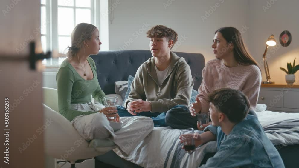 Group of teenage girls and boys at home hanging out laughing and talking in bedroom together with soft drinks and popcorn - shot in slow motion Group of teenage girls and boys at home hanging out laughing and talking in bedroom together with soft drinks and popcorn - shot in slow motion