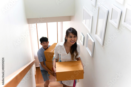 happy woman and man moving in new home. cheerful excited couple holding cardboard box to new house together. handsome boyfriend and beautiful girlfriend bonding by moving in an enjoyment fun place