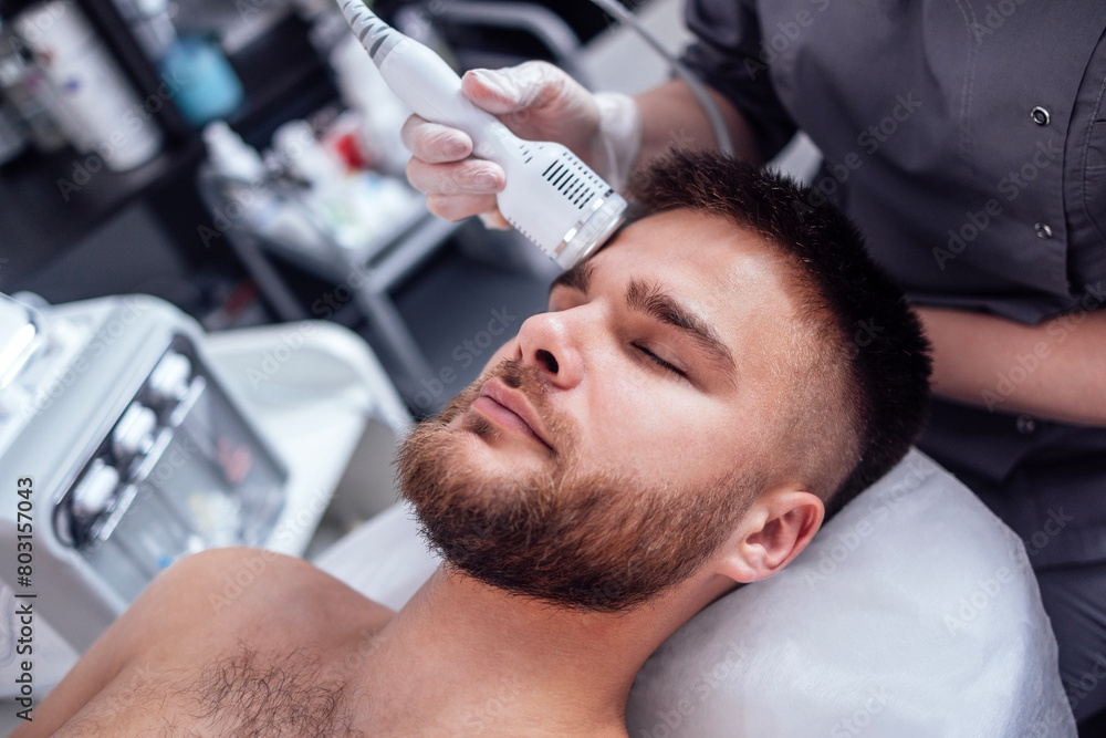 Closeup of face of beautiful relaxing man undergoing hardware cosmetology procedure in spa Closeup of face of beautiful relaxing man undergoing hardware cosmetology procedure in spa