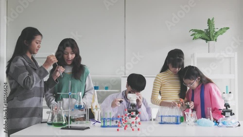 Group of Asian schoolchildren studying science and doing microscopic analysis in the laboratory photo