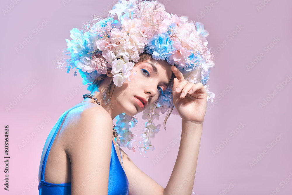 A beautiful woman with a wreath of flowers in a blue swimsuit on a pink background A beautiful woman with a wreath of flowers in a blue swimsuit on a pink background