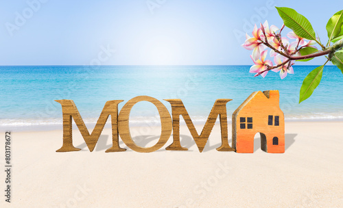 Mother's day card background idea, tropical style, mom wooden font and miniatrue wooden house model on tropical beach, outdoor day light