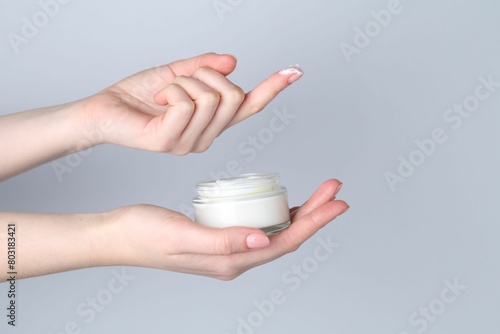 Woman with jar of cream on grey background  closeup. Space for text