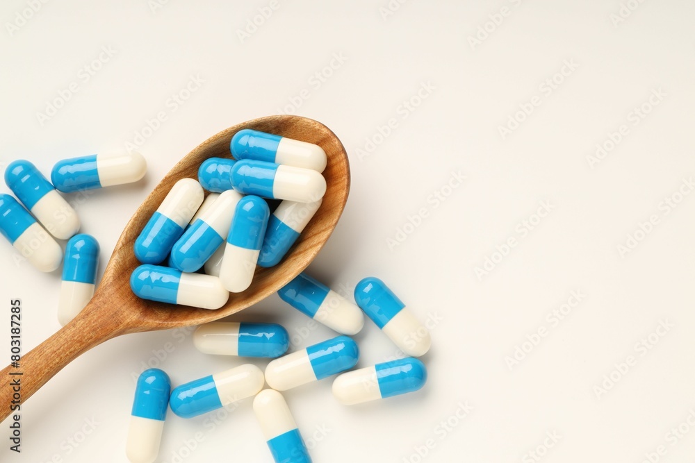 Antibiotic pills and spoon on white background, top view. Space for text Antibiotic pills and spoon on white background, top view. Space for text