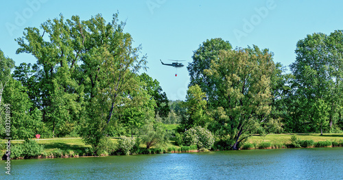 helicopter of the austrian armed forces with collapsible bucket during an exercise flight over the riparian bath (Aubad) in Tulln near the river Danube, Austria
