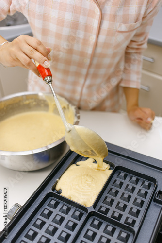 A young girl is cooking waffles.
