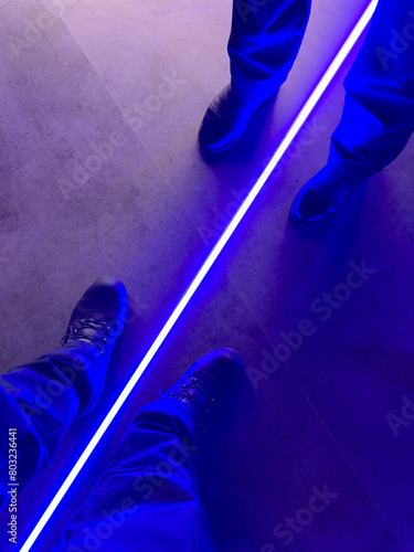 Legs of a woman and a man in blue neon color