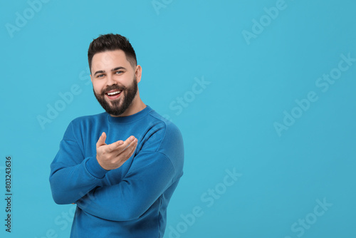 Portrait of happy young man with mustache on light blue background. Space for text