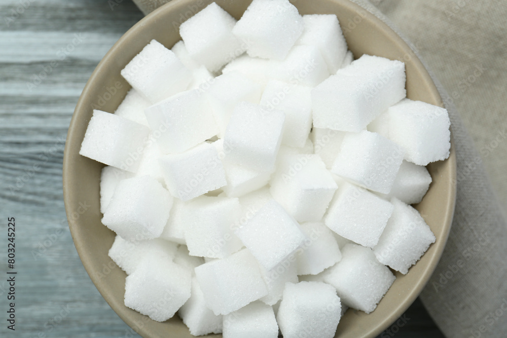 White sugar cubes in bowl on wooden table, top view White sugar cubes in bowl on wooden table, top view